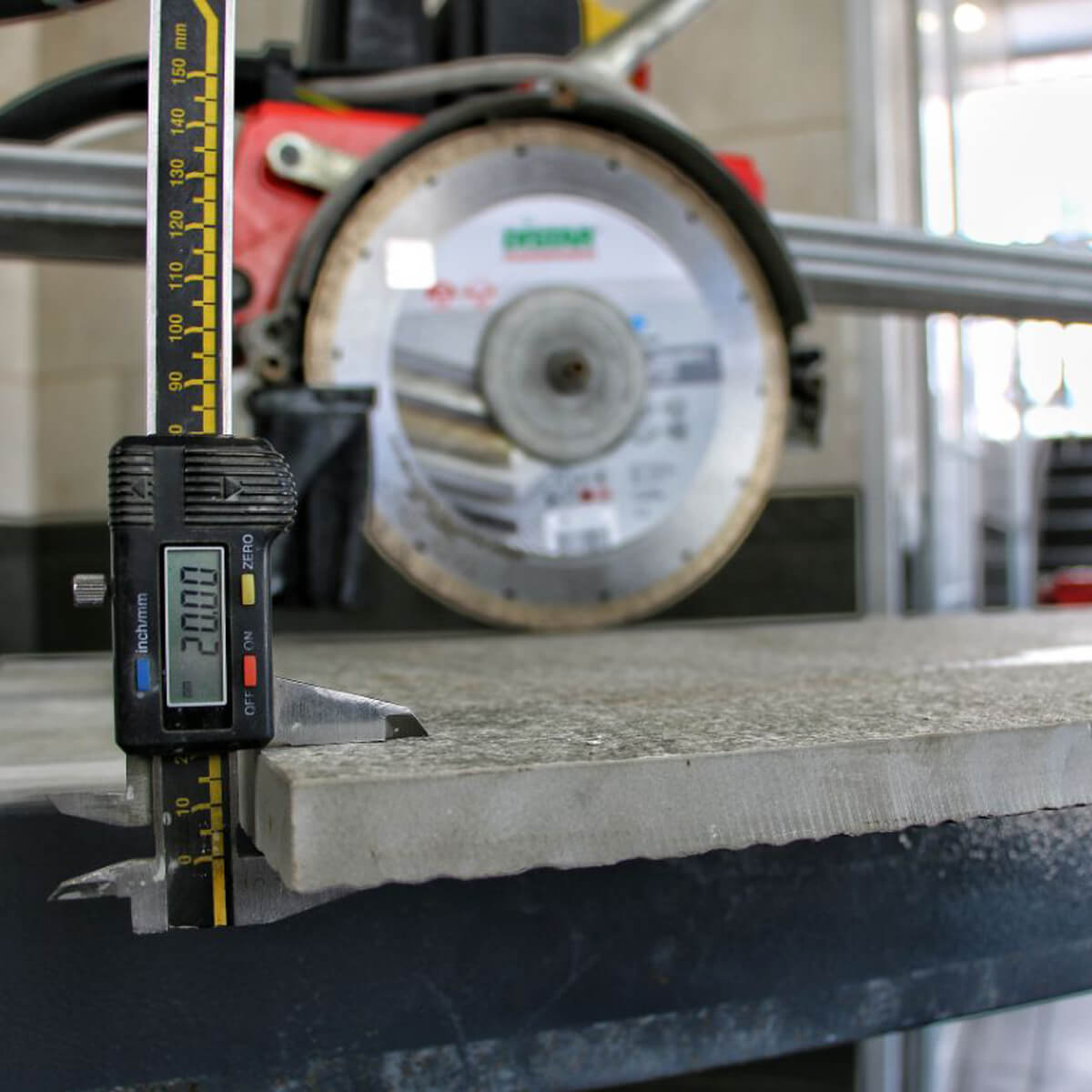 Digital caliper measuring a concrete slab with a circular saw in the background